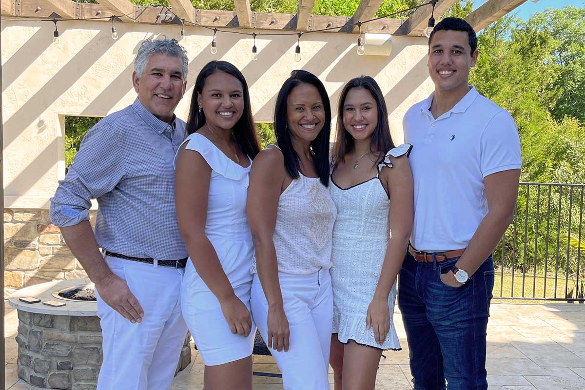 two parents and three children pose outside for a family photo